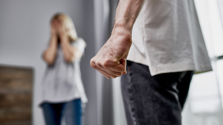 Woman covering face while man is intimidating her