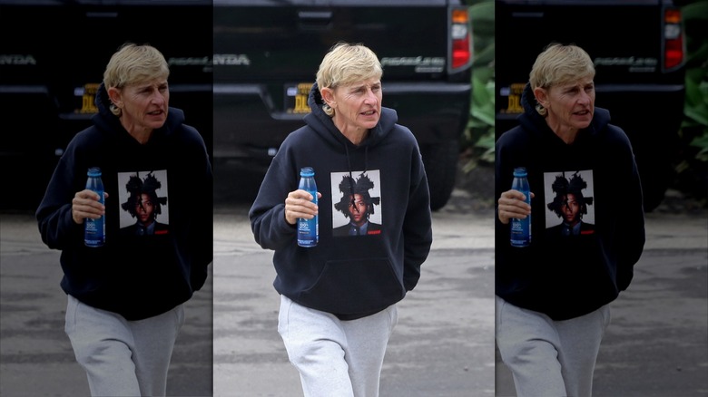 Makeup-free Ellen DeGeneres walking, holding bottle of water