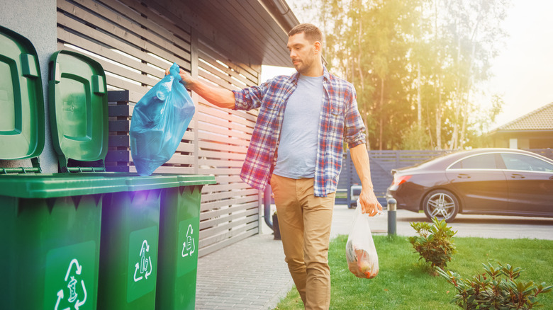 person putting bag in recycling bin