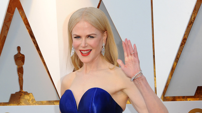 Nicole Kidman smiling with hand raised