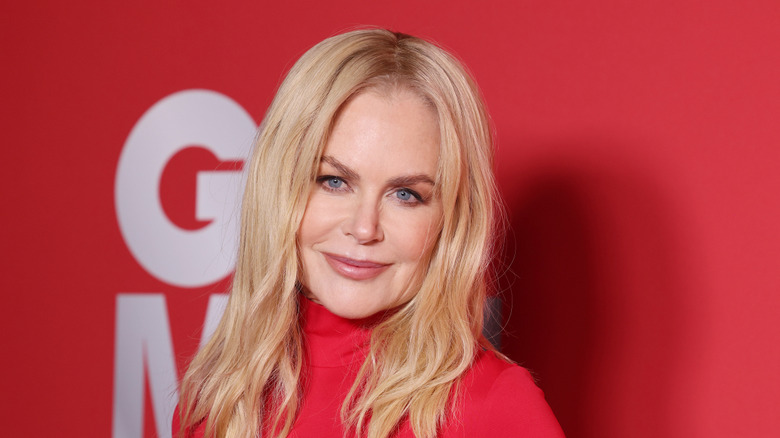 Nicole Kidman smiling an an event against a red background