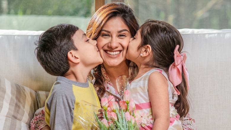 A woman being kissed by two children. 