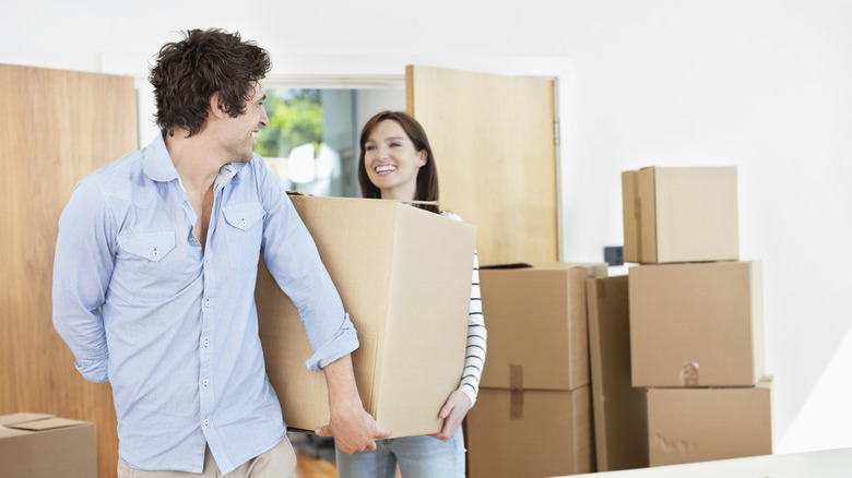 Man smiling, helping woman move