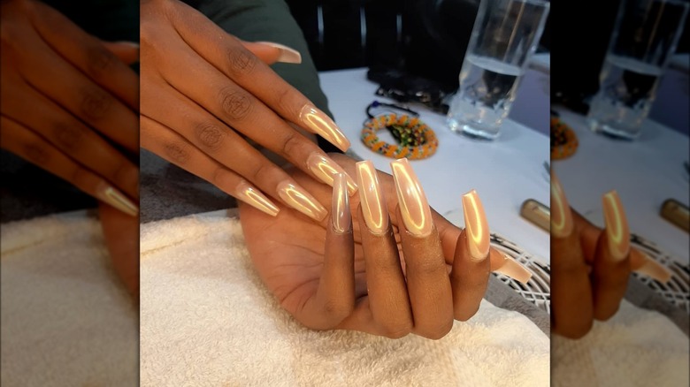 Hands showing long nails with reflective gold finish