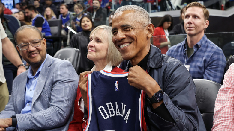 Barack Obama holds up an Obama jersey at a Clippers game