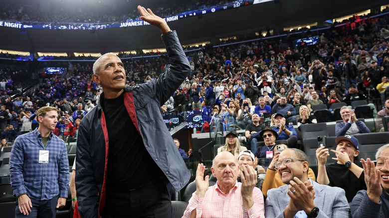 Barack Obama waves to the crowd at a basketball game.