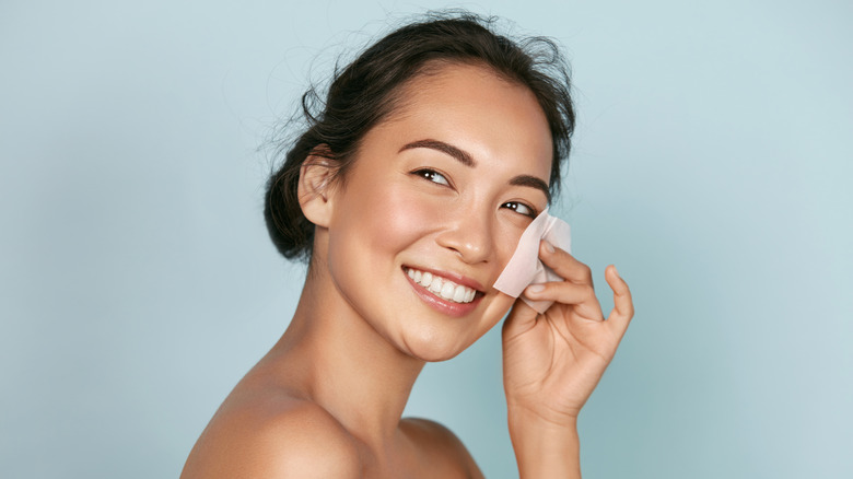 Woman blotting her skin with paper 