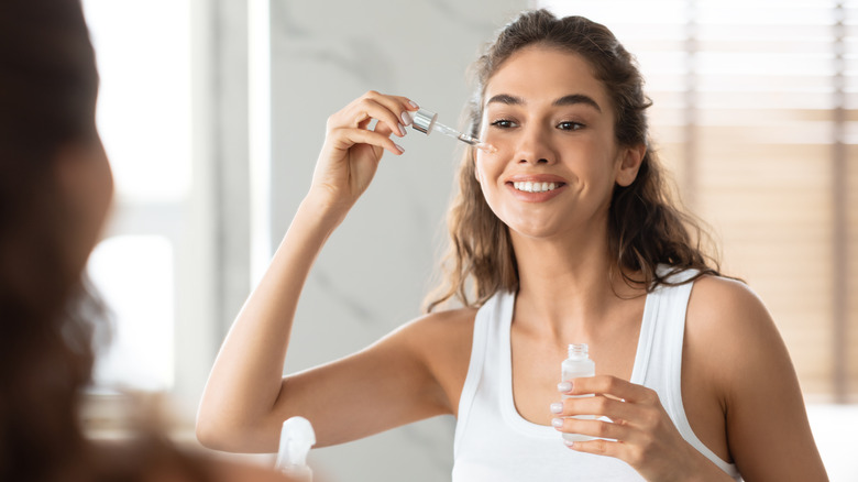 Woman applying serum to face