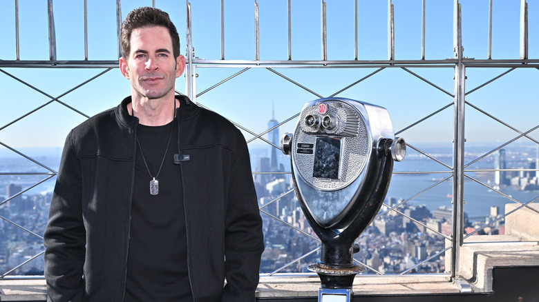 Tarek El Moussa posing at the Empire State Building with the skyline in the background