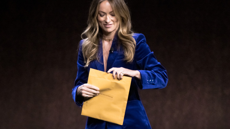 Olivia Wilde opens custody papers from Jason Sudeikis onstage