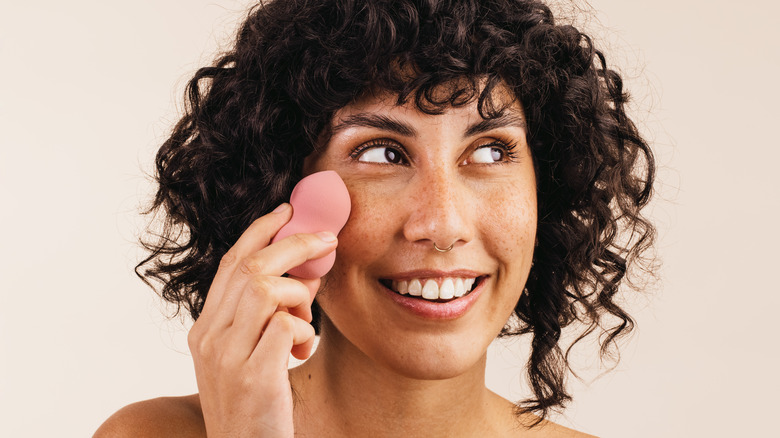 Woman holding makeup sponge 