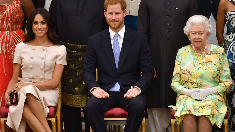 Meghan Markle, Prince Harry and the queen sitting at an event