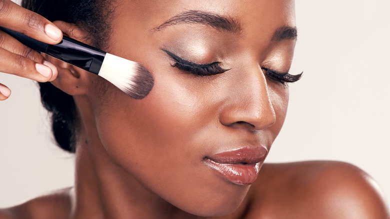 Black woman using blush