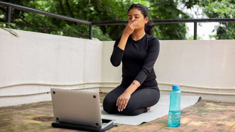 woman doing breathing exercises on yoga mat 