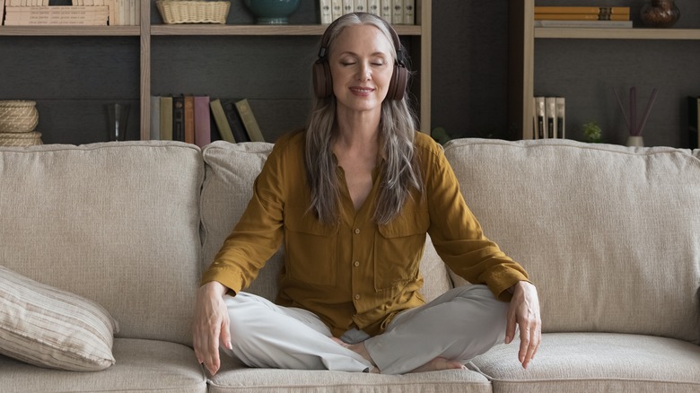 woman meditating at home with headphones