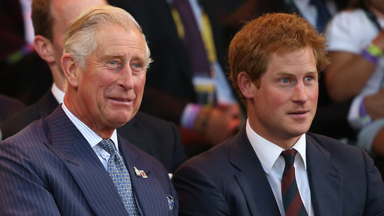 King Charles smiling and Prince Harry looking intent