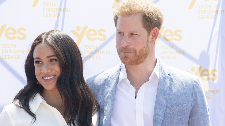 Meghan Markle and Prince Harry smiling looking off to the side