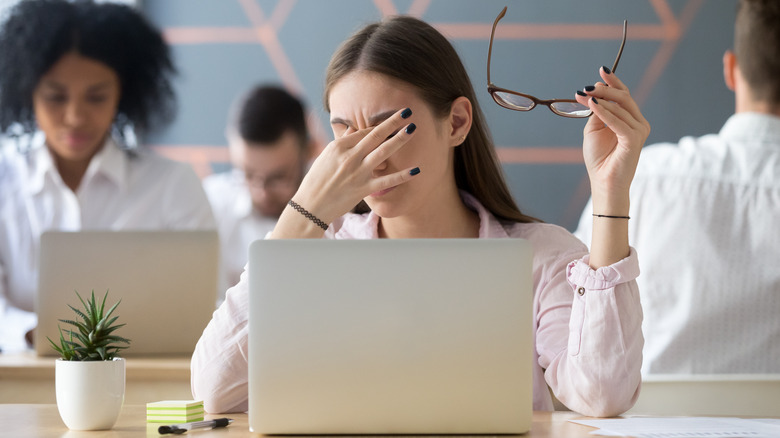 Woman squinting taking off glasses