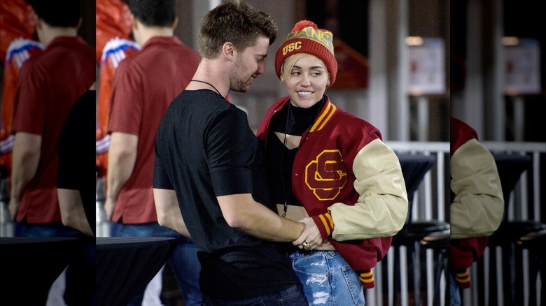 Miley Cyrus and Patrick Schwarzenegger grasping each other 