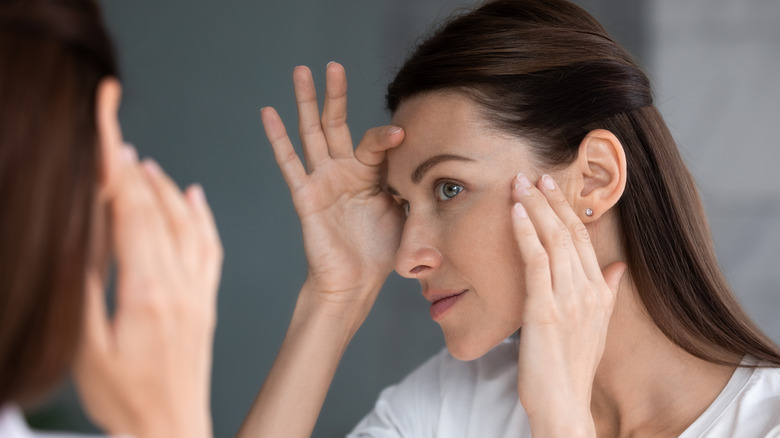 Woman looking at skin in mirror