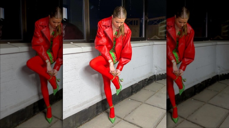 women in red jacket fixing shoe