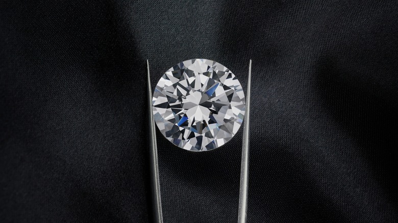 Round diamond held by tweezers