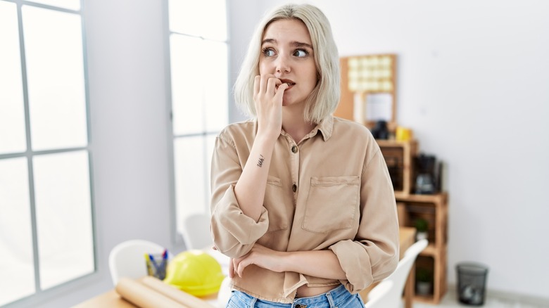 Woman looking afraid chewing fingers