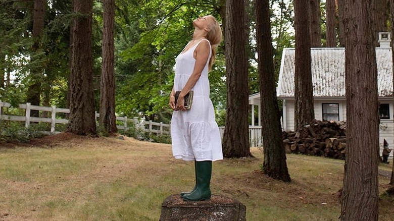 Pamela Anderson standing on a tree stump