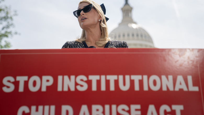 Paris Hilton in front of Capitol Hill with "Stop Institutional Child Abuse Act" sign