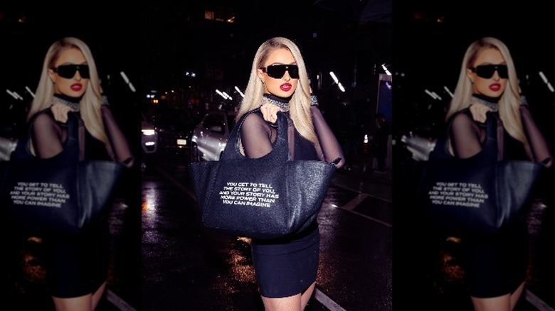 Paris Hilton holding bag with message on it