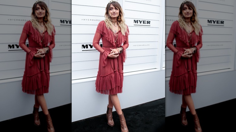 Paris Jackson posing in red fringe dress and brown leather boots