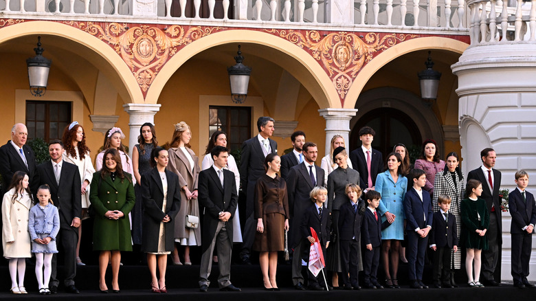 The royal family of Monaco stand in a line in front of a royal building.