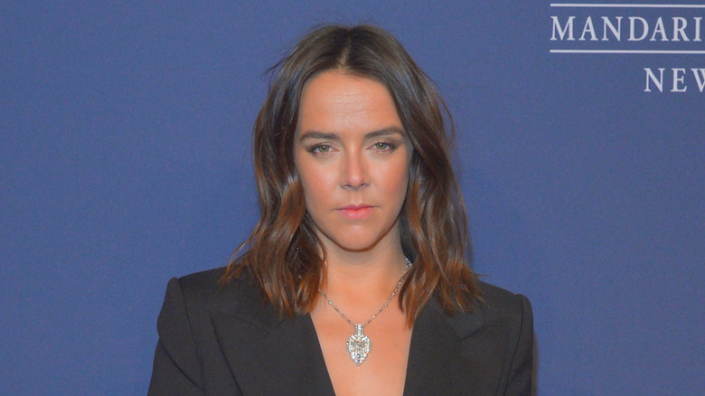 Pauline Ducruet stands in front of a blue background wearing a blazer and looking into the camera.