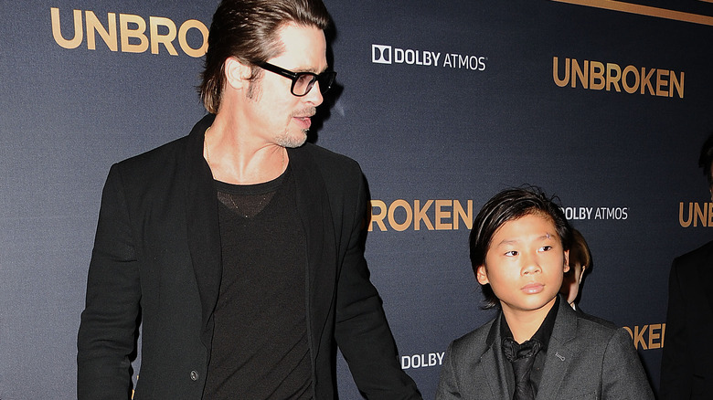 Brad Pitt guides Pax Jolie-Pitt by the arm