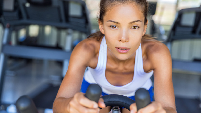 Woman wearing blue sports bra riding an exercise bike.