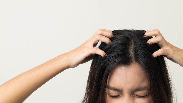 woman scratching scalp wincing