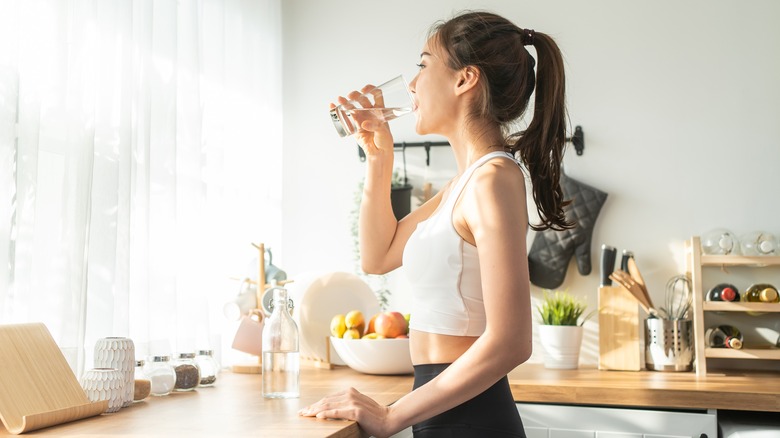 person drinking water in kitchen