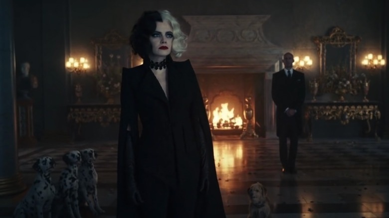 Cruelle De Vil standing in front of a fireplace with dogs