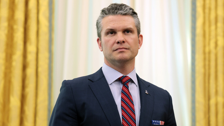 Pete Hegseth stands and listens
