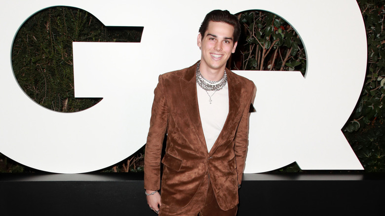 Paris Brosnan smiles in front of the GQ logo at a GQ Man of the Year party.