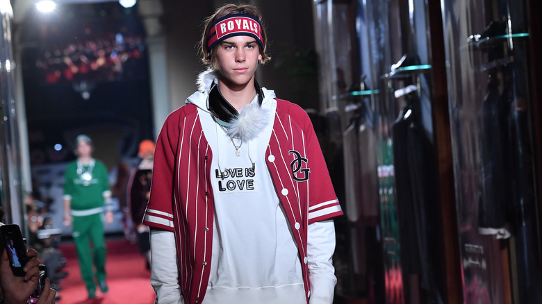 Paris Brosnan walks the runway during a Dolce and Gabbana show in red sports clothes.