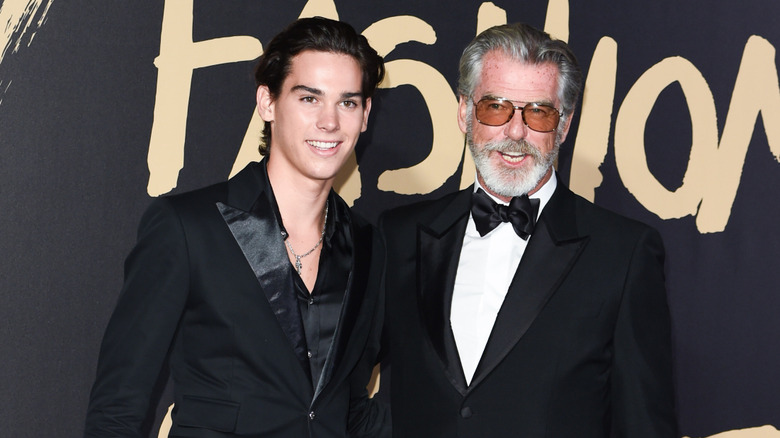 Paris and Pierce Brosnan pose on the red carpet together in black suits.