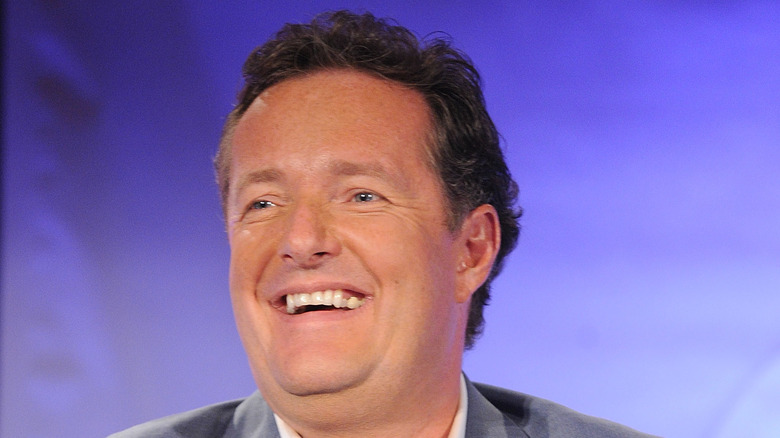 Piers Morgan smiles onstage at an event