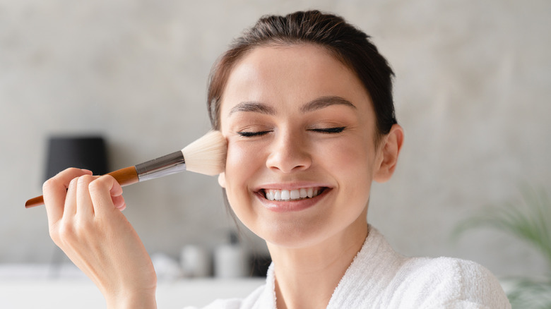 Smiling woman with makeup brush