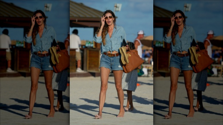 woman walking on beach in denim shorts