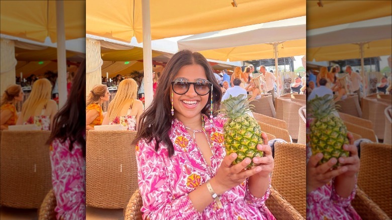 Brunette in sunglasses holding a pineapple