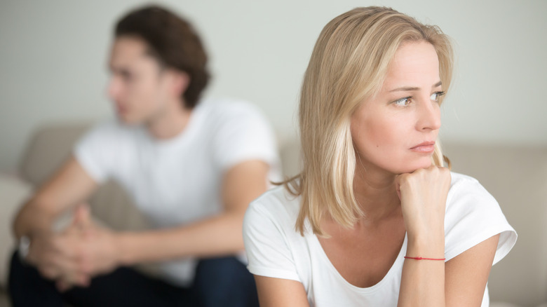 angry man sitting behind frustrated woman