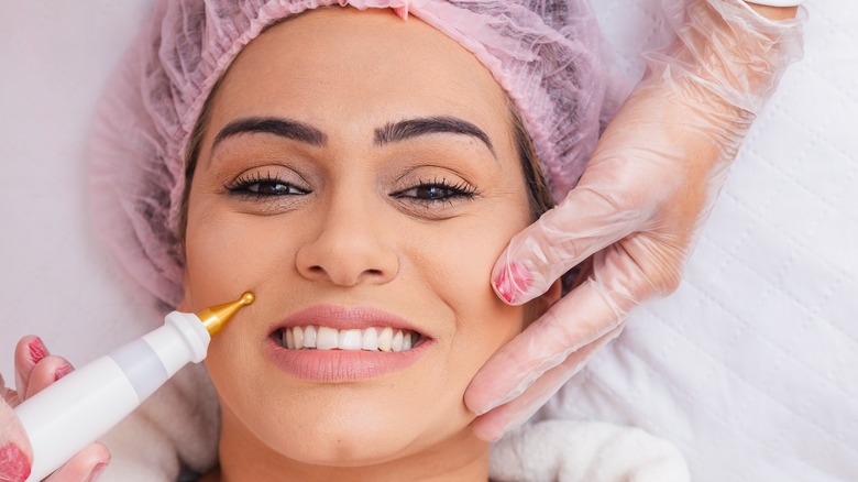 A woman smiling while receiving plasma pen treatment 