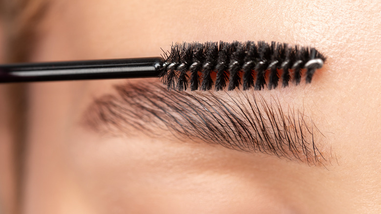 eyebrow brush being combed through eyebrows