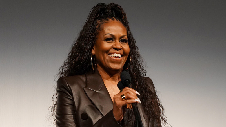 Michelle Obama laughing on stage holding mic